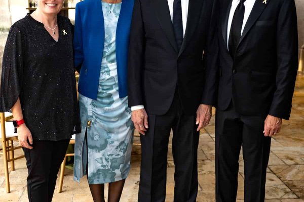Group of four smiling people at Believe Ball event under a tent.
