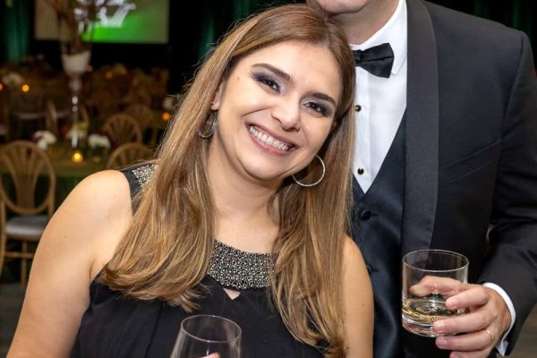 Elegant couple at Believe Ball event with wine glasses and formal attire.