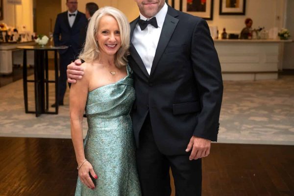 Elegant couple at Believe Ball charity event in formal attire.