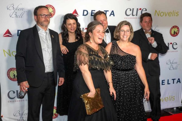 Group of people at Believe Ball event, smiling and dressed formally.