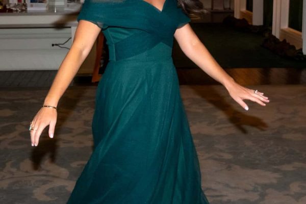 Woman in elegant teal gown dancing at Believe Ball event.