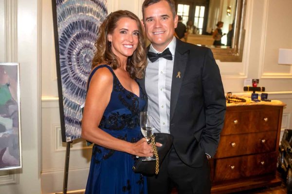 Elegant woman in blue gown and man in tuxedo at Believe Ball event.