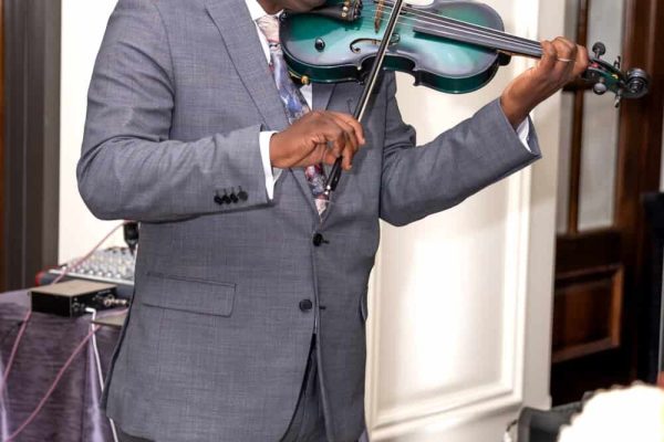 Man playing violin at Believe Ball event in formal suit.