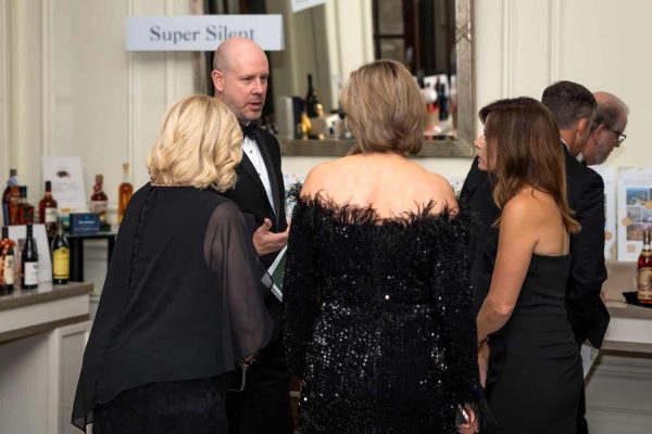 Group of people in formal attire at Believe Ball event in a bar area.