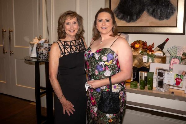 Two women smiling at a charity event with Believe Ball branding.