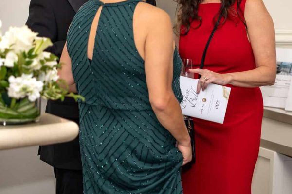 Women and man engaged in conversation at Believe Ball event.
