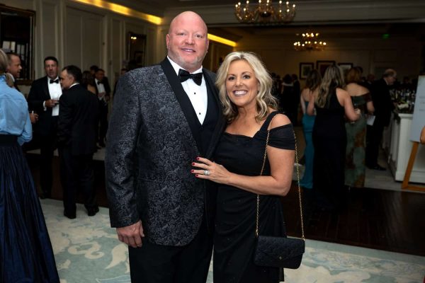 Elegant couple at Believe Ball event in formal attire, smiling for the camera.