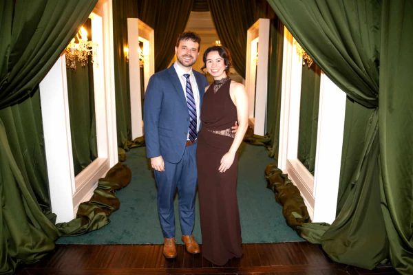 Elegant couple at Believe Ball event in a luxurious green and gold decorated venue.