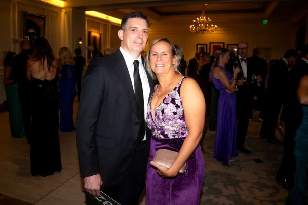 Elegant couple at Believe Ball charity event in formal attire.
