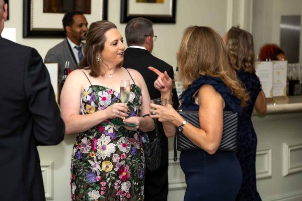 Women in elegant dresses chatting at a formal event.