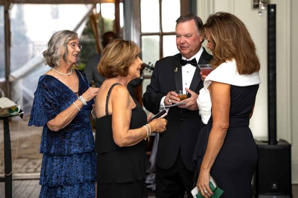 Elegant group of people at a formal event, engaging in conversation.