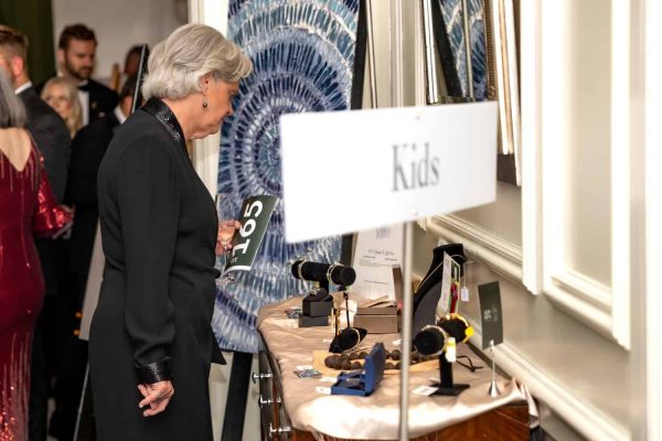 Woman viewing jewelry display at Believe Ball charity event.